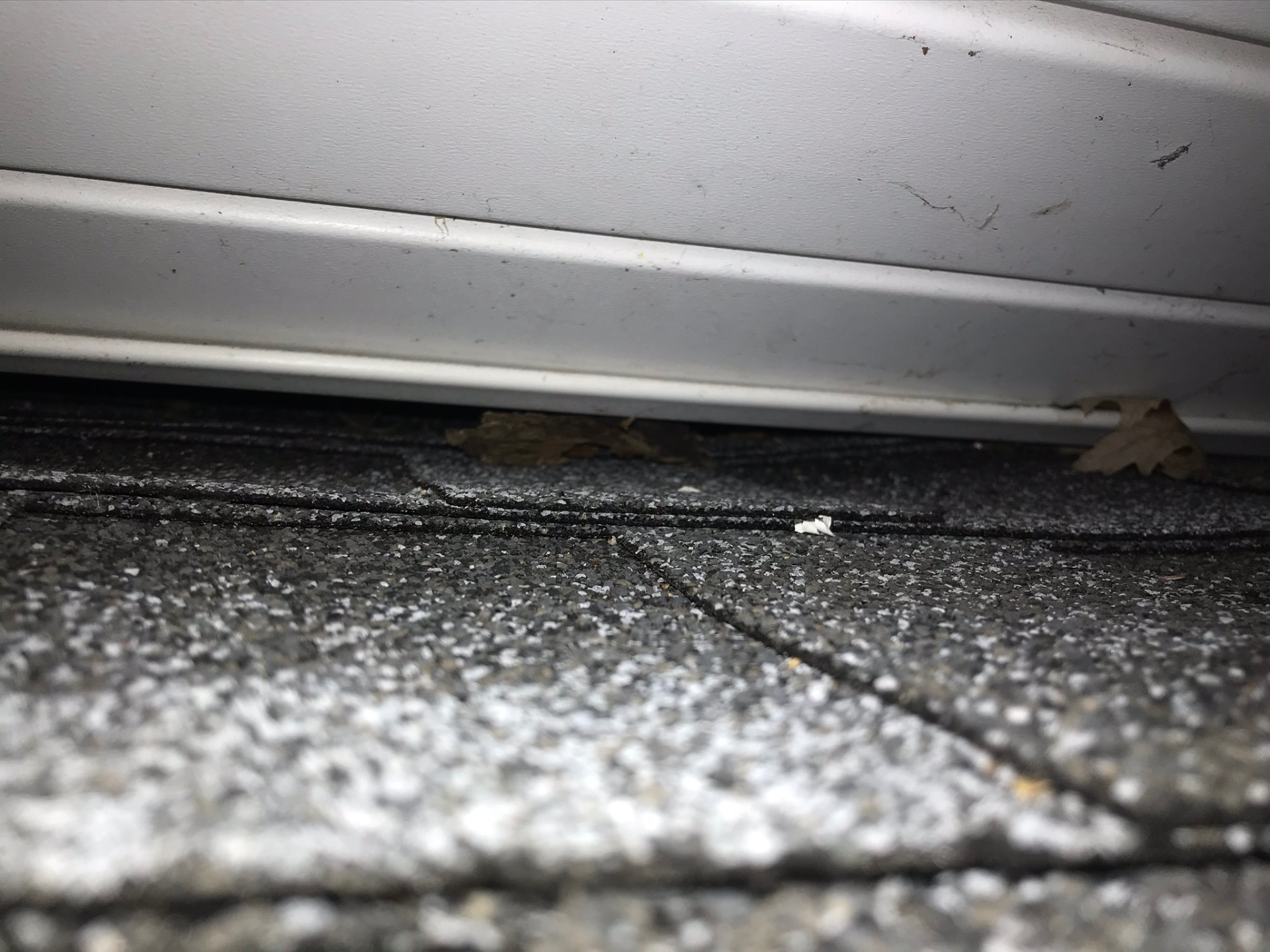 Gap between a white soffit board and the shingle course below it